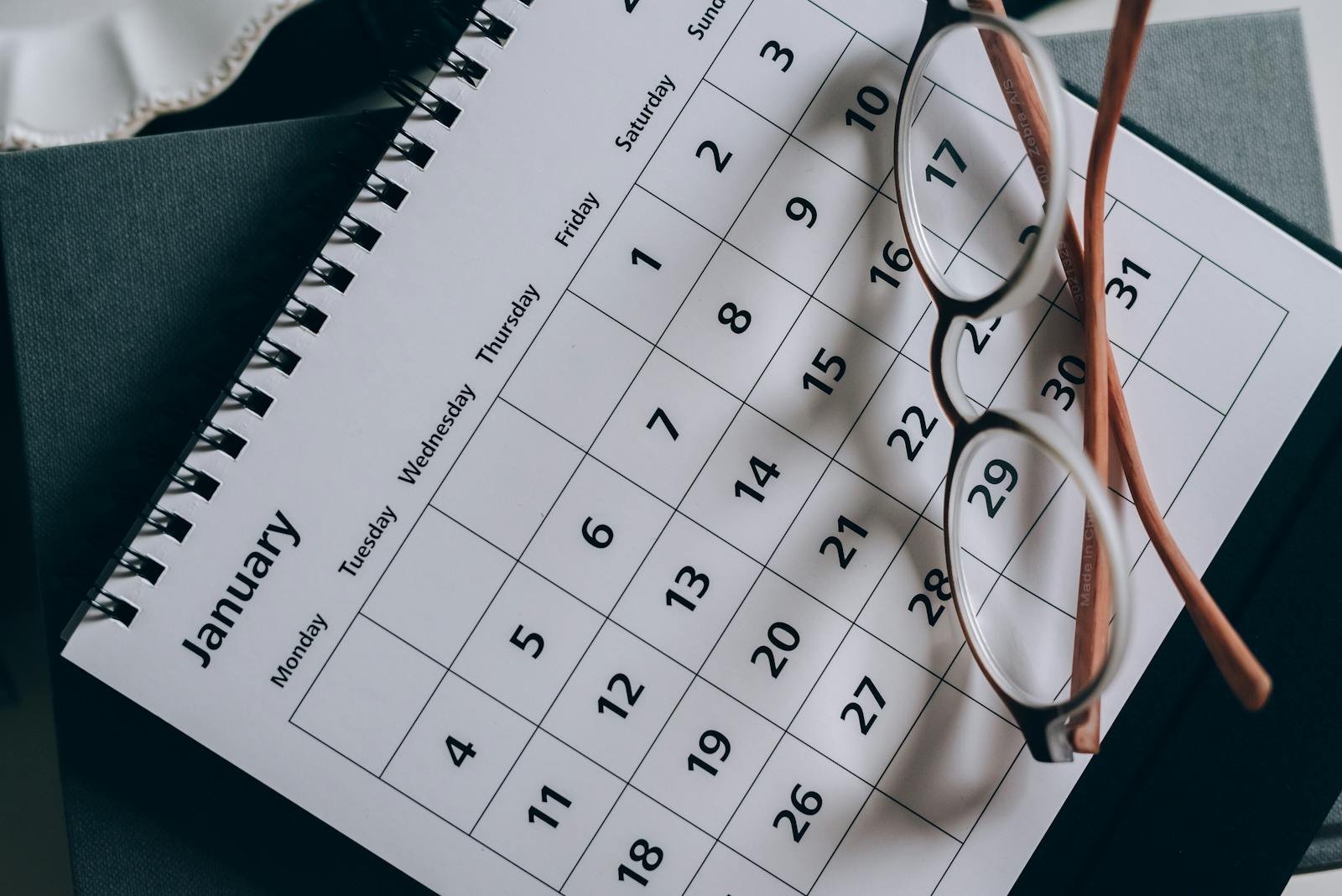 Kalender mit Januar-Seite und Lesebrille auf einem Tisch, symbolisiert den Pflichtstart der E-Rechnung im Januar 2028.