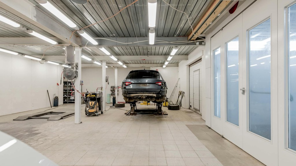 Aufnahme von Renee Razumov aus einer Garage zeigt ein Auto auf einer Hebebühne, bereit für Reparaturen.
