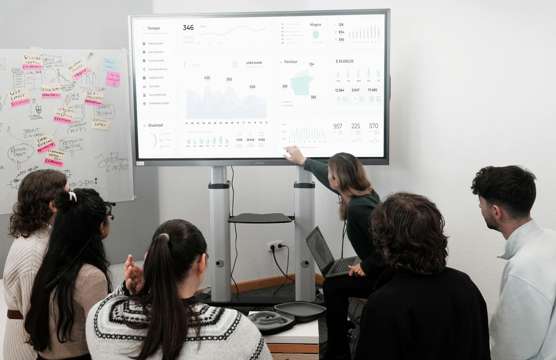 Team in einem modernen Büro betrachtet ein großes Daten-Dashboard mit Diagrammen.