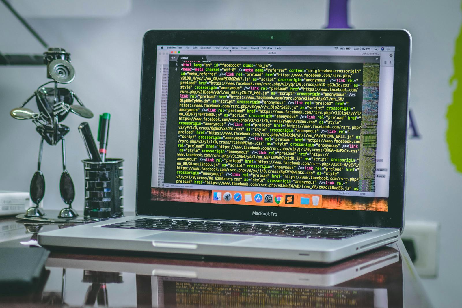 MacBook Pro auf einem Schreibtisch zeigt Programmcode im Editor.